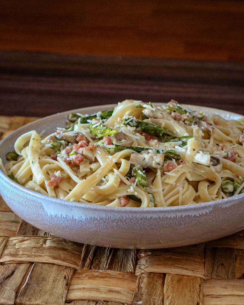 Creamy fettuccine with ham and asparagus in a wide bowl.