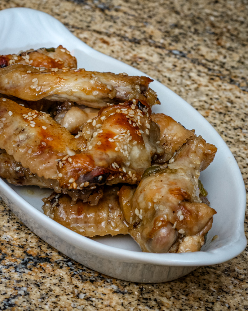 A small serving plate with honey garlic chicken wings.