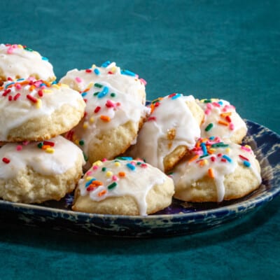 Iced and decorated ricotta cookies on a pottery tray.