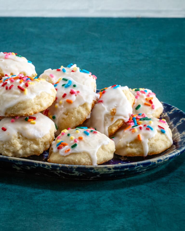 Iced and decorated ricotta cookies on a pottery tray.