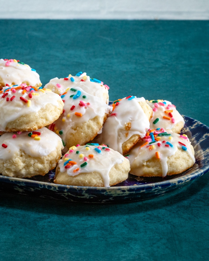 Iced and decorated ricotta cookies on a pottery tray.