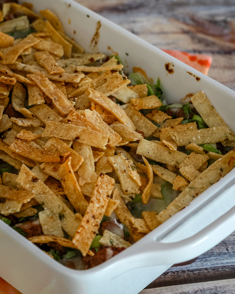 Taco bake in a baking dish with tortilla strips for topping.