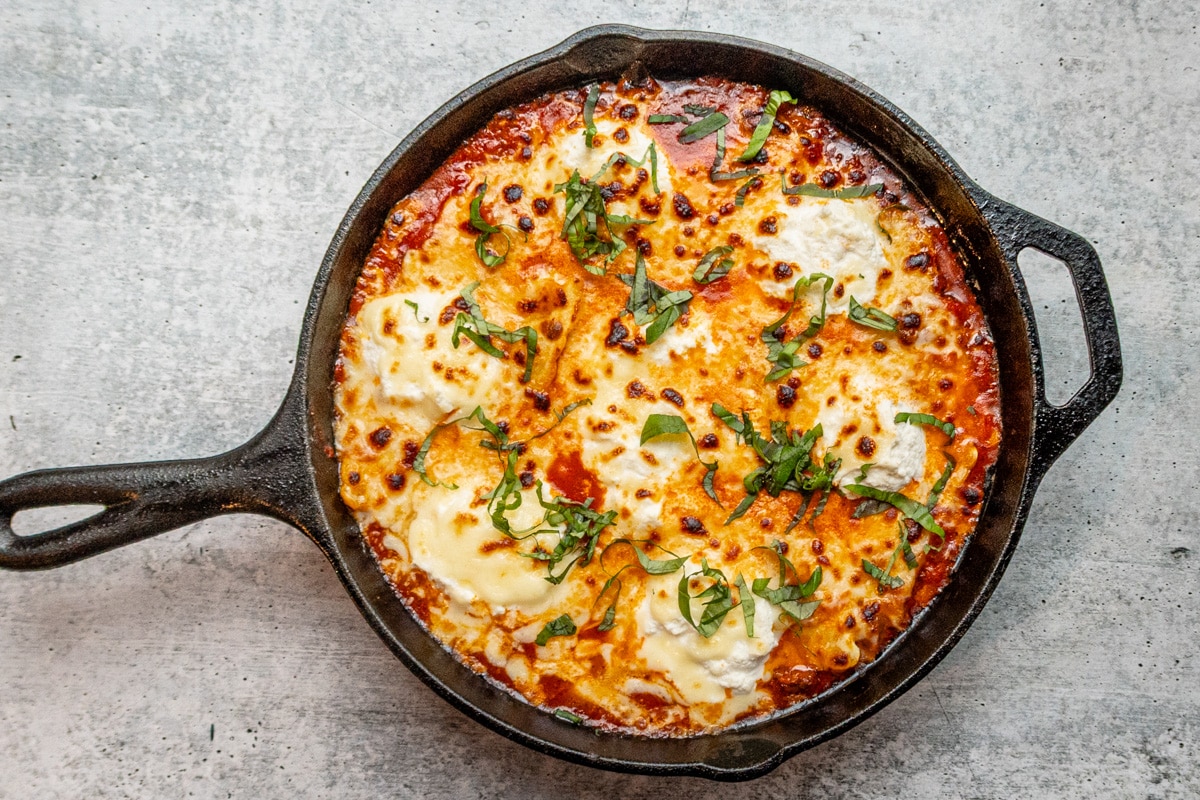 Lazy skillet lasagna with cheese topping and basil garnish.