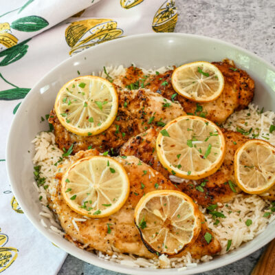 A serving dish with lemon pepper chicken on rice