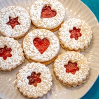 A plate of linzer cookies with jam peeking through the cutouts.