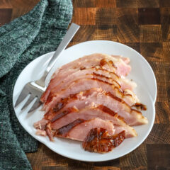 Sliced maple and brown sugar glazed ham on a serving platter.