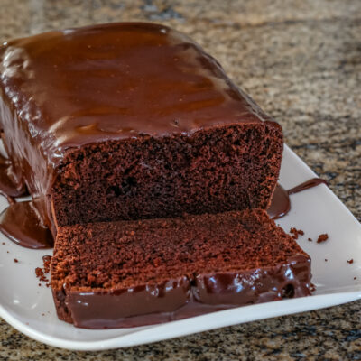 Iced chocolate loaf cake on a serving plate.