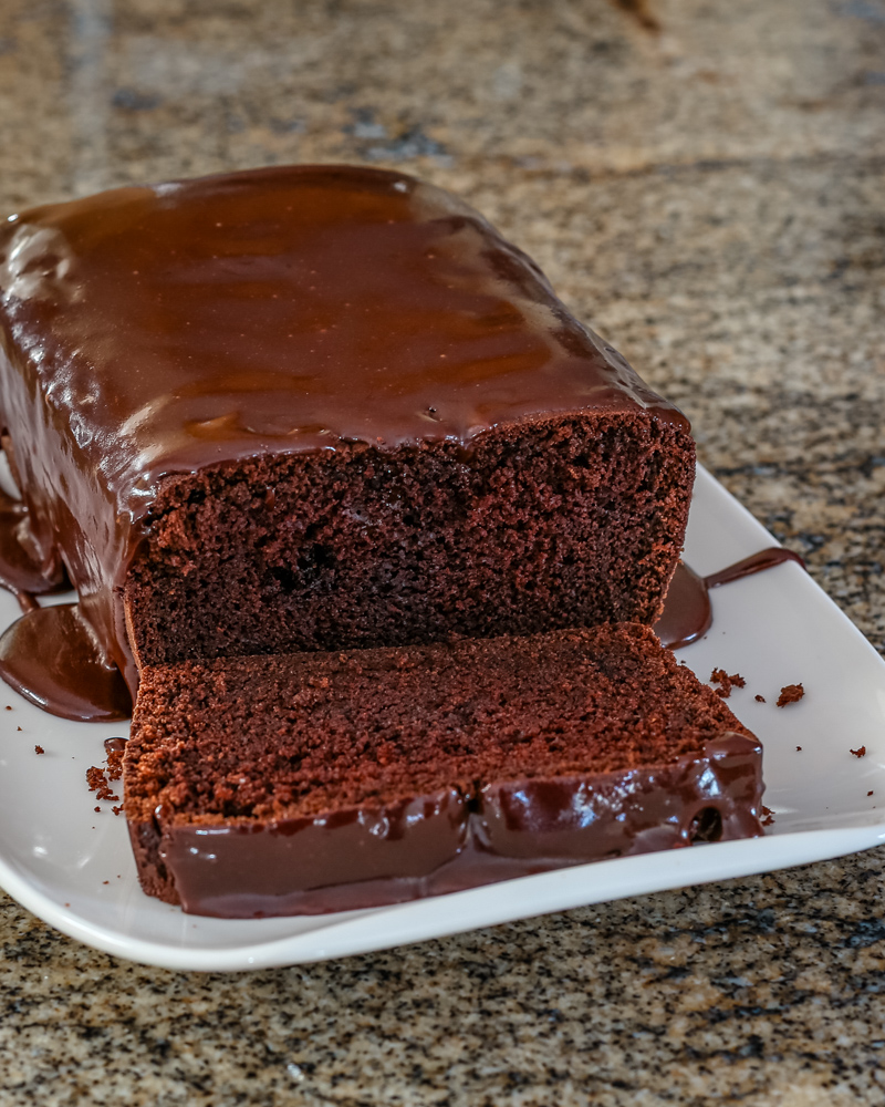 Iced chocolate loaf cake on a serving plate.