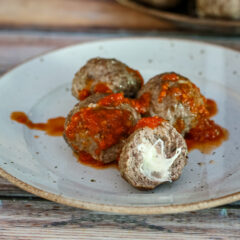 Mozzarella stuffed meatballs with marinara sauce on a plate.