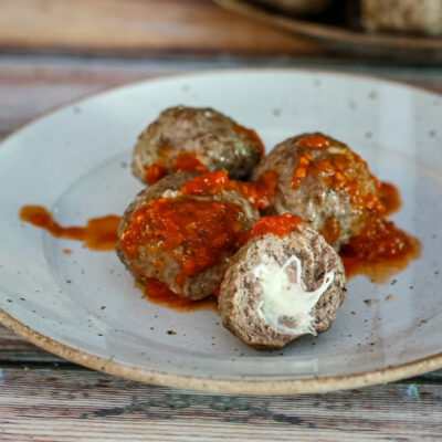 Mozzarella stuffed meatballs with marinara sauce on a plate.