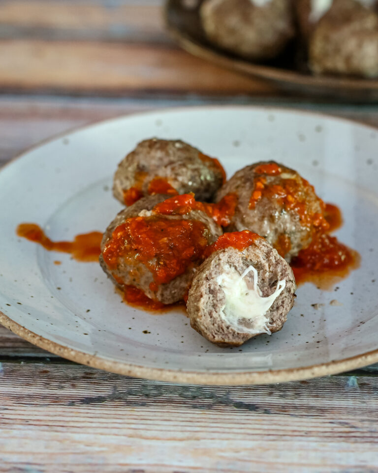 Mozzarella stuffed meatballs with marinara sauce on a plate.