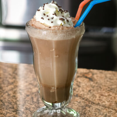 A chocolate ice cream soda with whipped cream and sprinkles.