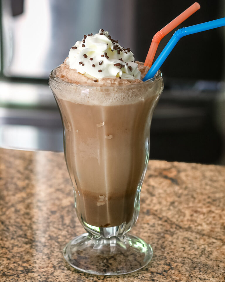 A chocolate ice cream soda with whipped cream and sprinkles.