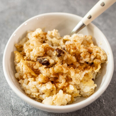 A small bowl of rice pudding with spoon.