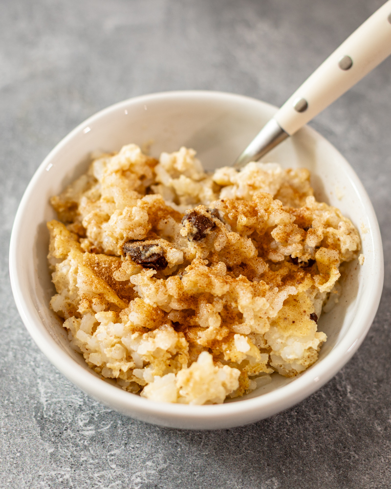 A small bowl of rice pudding with spoon.