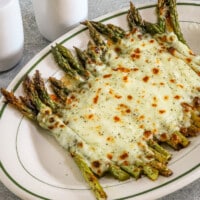 Salt and pepper asparagus with mozzarella cheese on a serving plate.