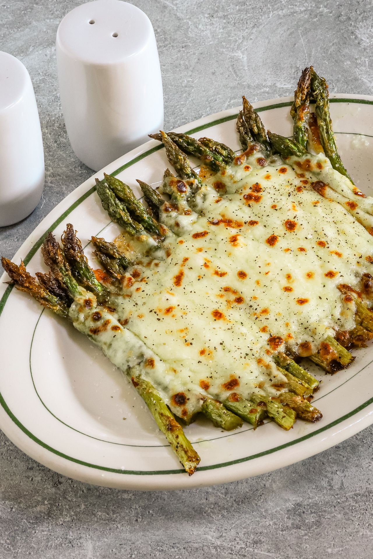 Salt and pepper asparagus with mozzarella cheese on a serving plate.