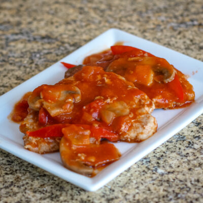 pork cutlets on a serving plate with a Marengo style sauce.