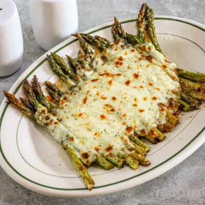 Salt and pepper asparagus with mozzarella cheese on a serving plate.