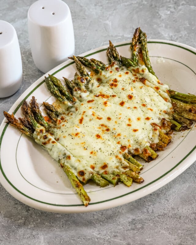 Salt and pepper asparagus with mozzarella cheese on a serving plate.