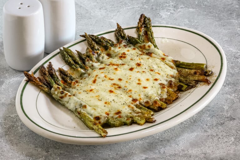 Salt and pepper asparagus with mozzarella cheese on a serving plate.