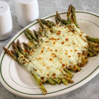 Salt and pepper asparagus with mozzarella cheese on a serving plate.