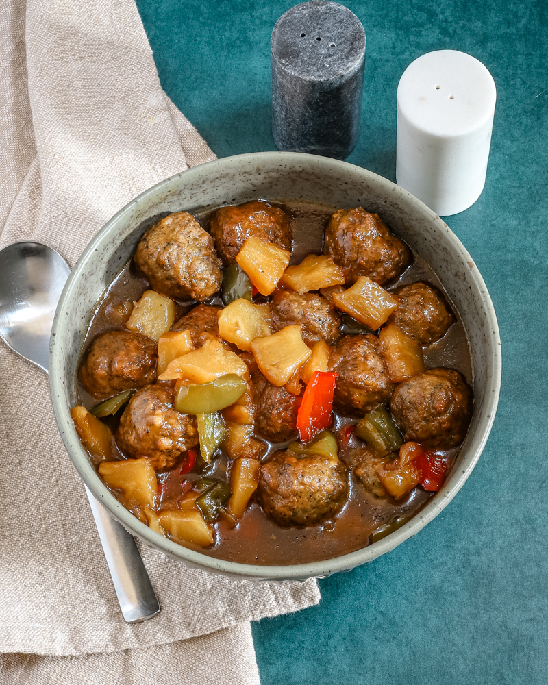 Slow cooker sweet and sour meatballs with bell pepper and pineapple chunks.