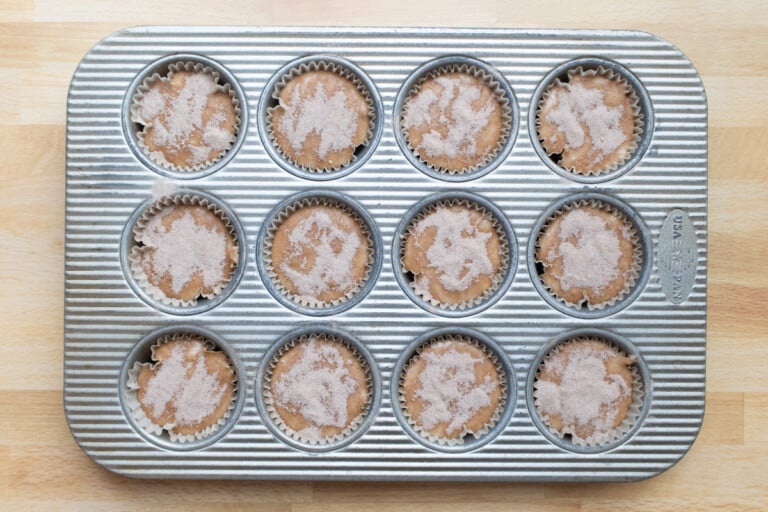 Topping the muffin batter with cinnamon-sugar.