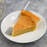 A slice of chess pie on a white plate with a fork.