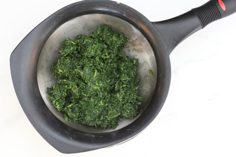 Frozen spinach in a strainer.
