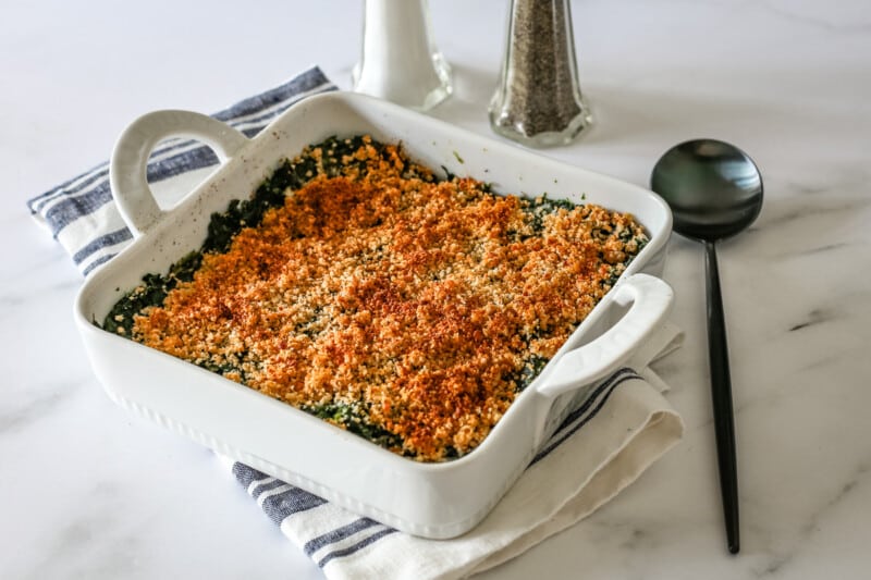 A spinach casserole in a baking dish with crumb topping.