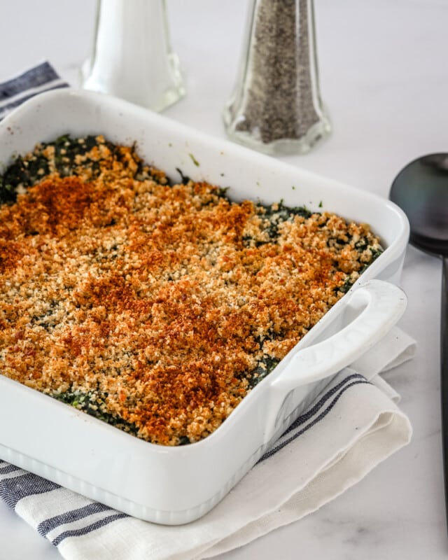 A spinach casserole in a baking dish with crumb topping.