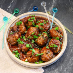 Teriyaki meatballs served as an appetizer with picks and a garnish of green onion tops.