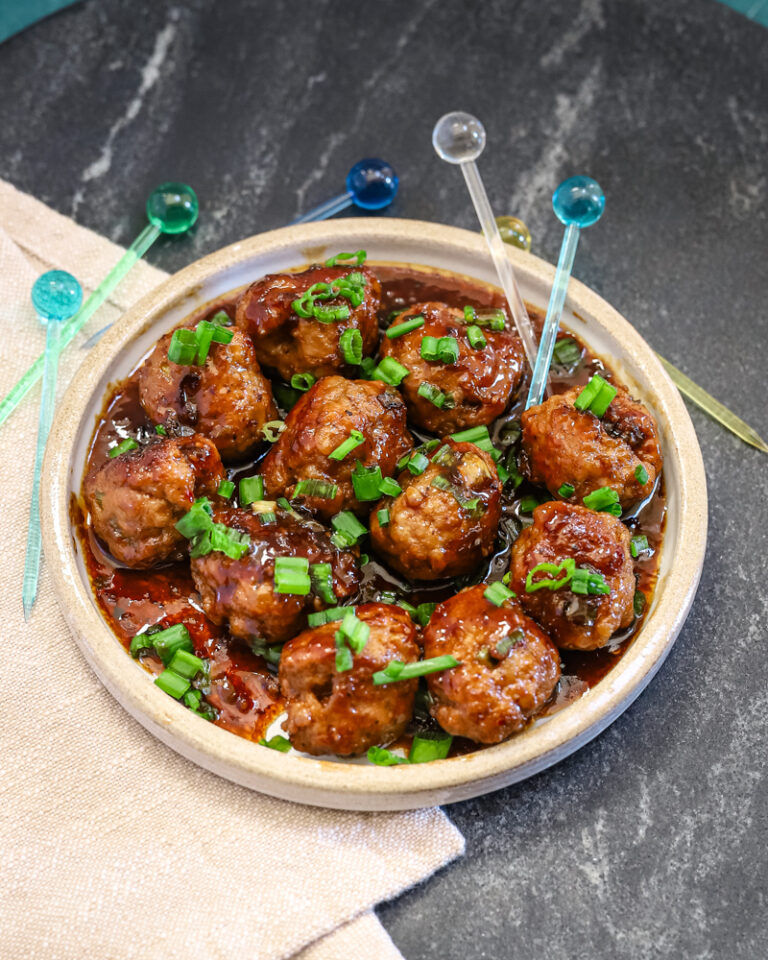 Teriyaki meatballs served as an appetizer with picks and a garnish of green onion tops.