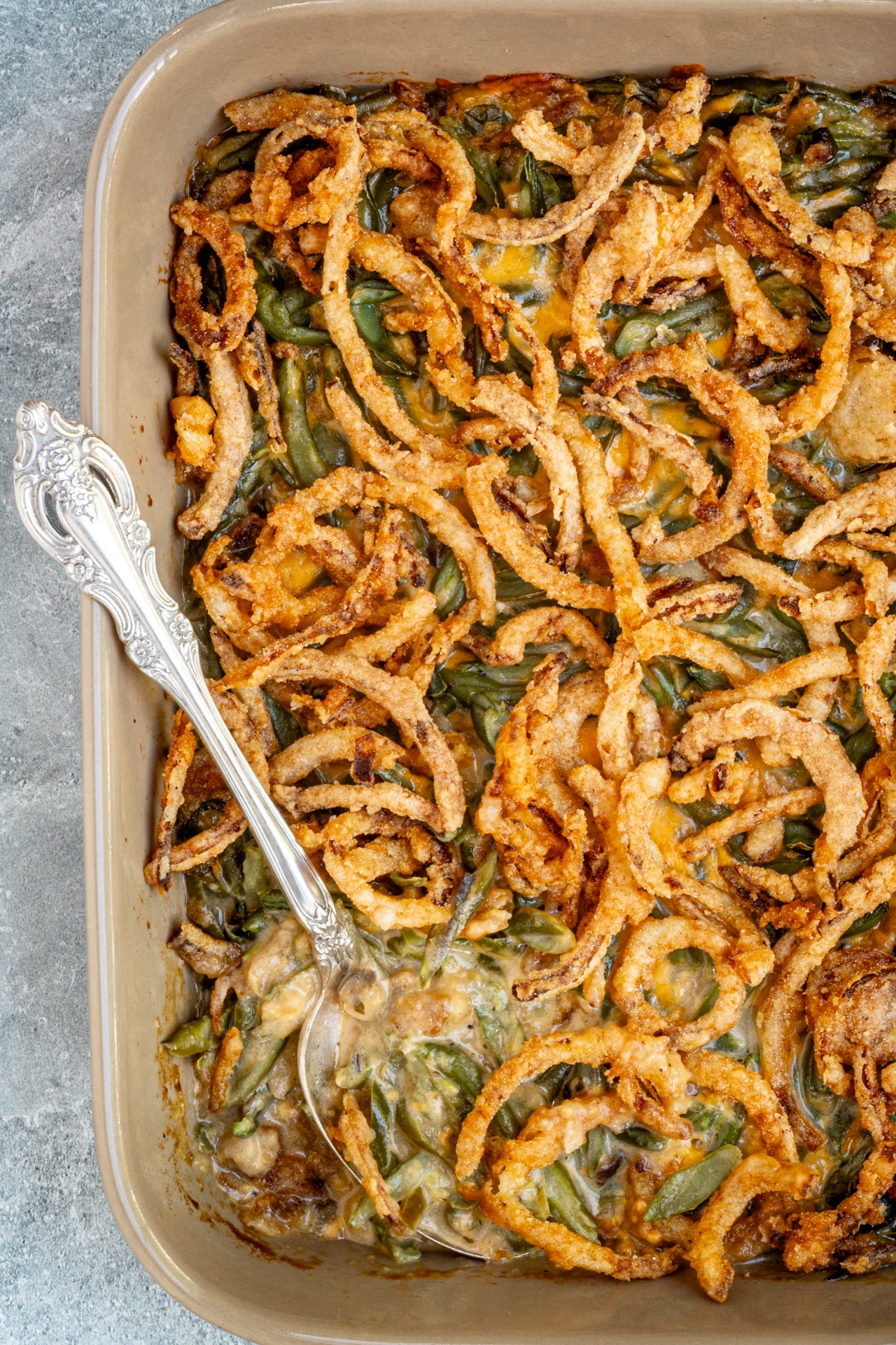 Green bean casserole in a baking dish with a serving spoon.