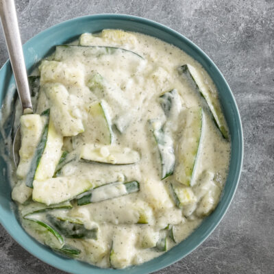 A serving bowl so zucchini in a sour cream and dill sauce.