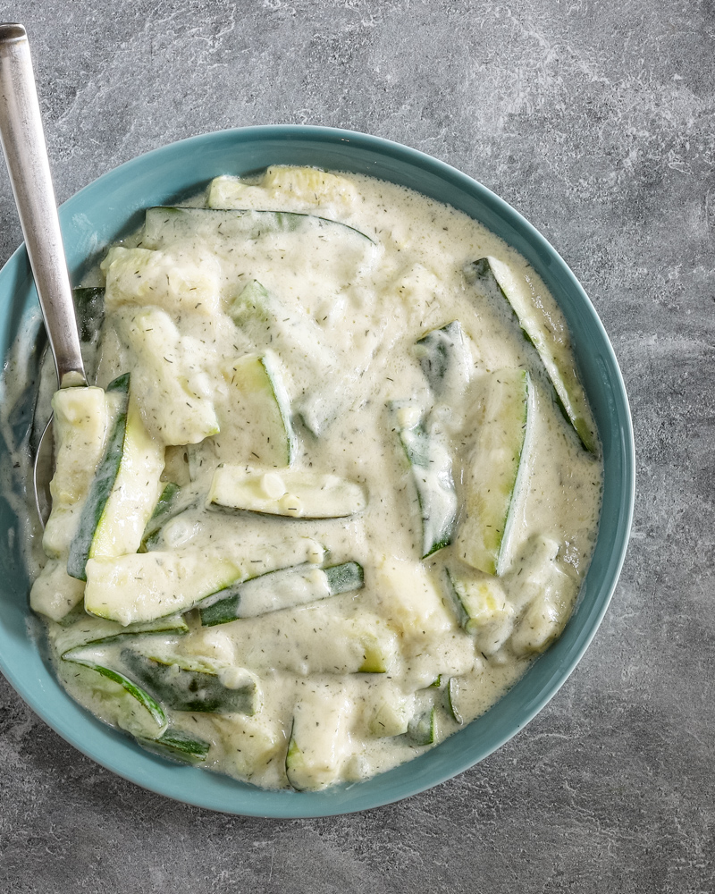 A serving bowl so zucchini in a sour cream and dill sauce.