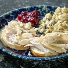 a hot turkey sandwich with leftover stuffing, cranberry sauce, and gravy