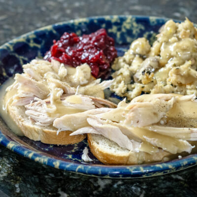 a hot turkey sandwich with leftover stuffing, cranberry sauce, and gravy