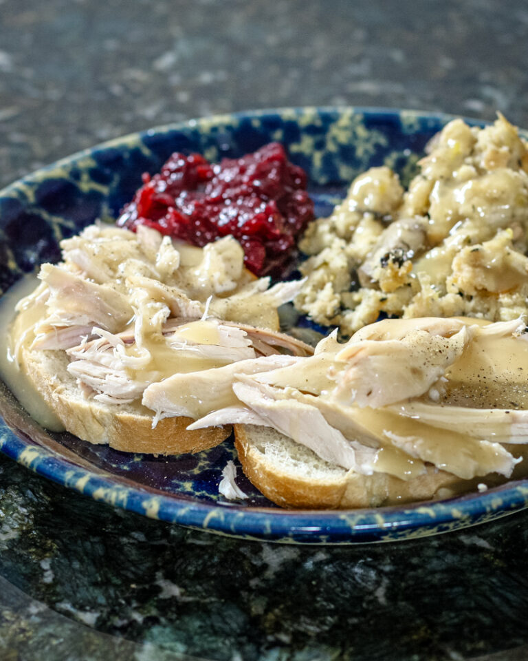 a hot turkey sandwich with leftover stuffing, cranberry sauce, and gravy