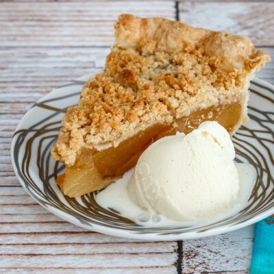 A slice of apple crumble pie with ice cream.