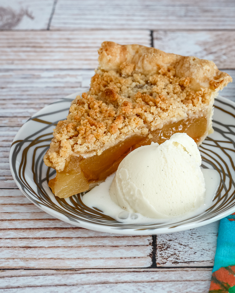 A slice of apple crumble pie with ice cream.
