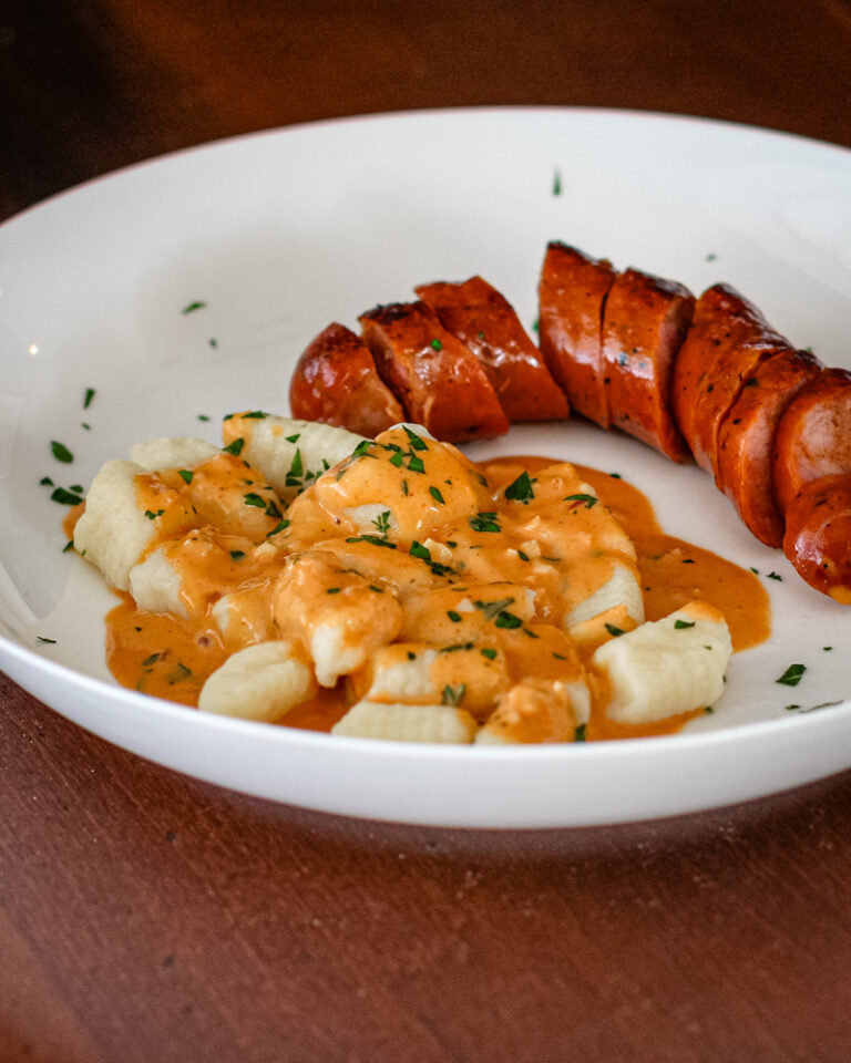 homemade gnocchi on a plate with andouille sausage and a sauce