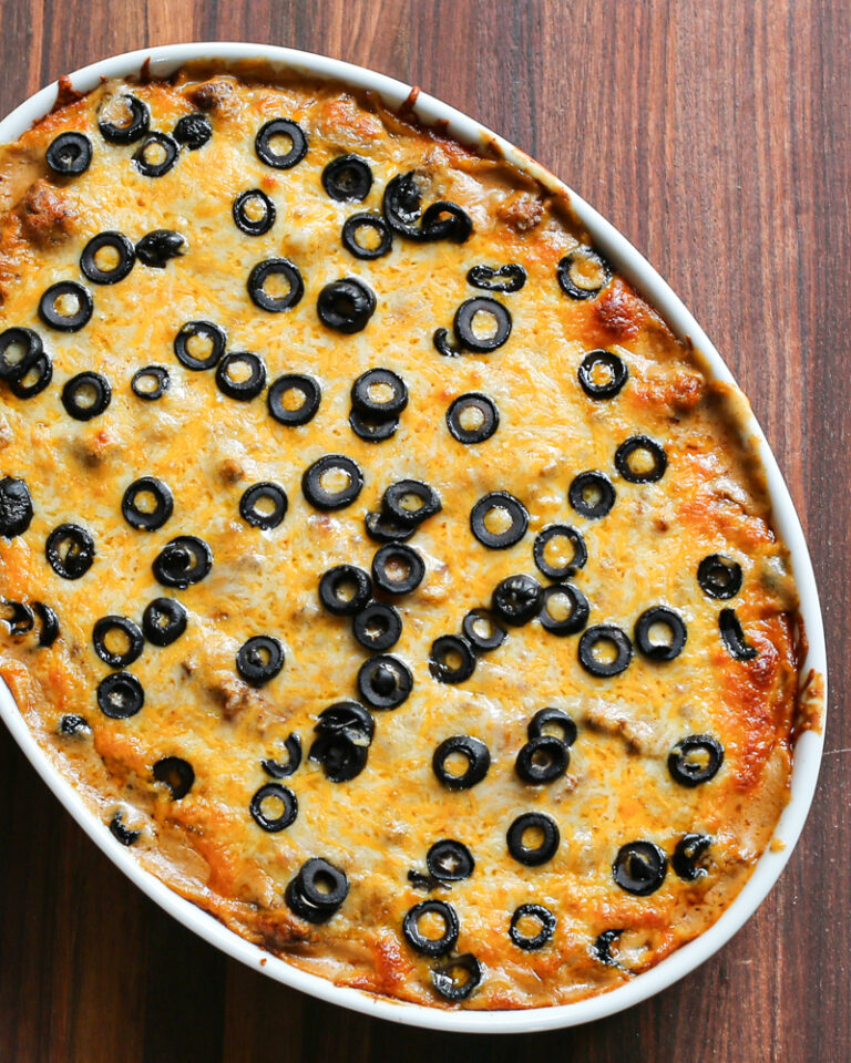 Overhead photo of a beef enchilada casserole with a topping of cheese and black olives.