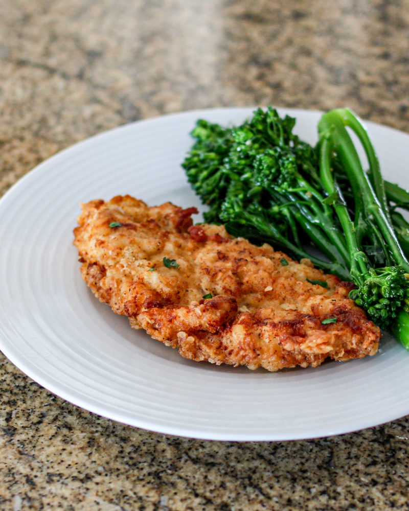 fried chicken breast cutlets on a plate with broccolini