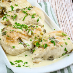 Baked chicken breasts topped with creamy sauce and green onions.