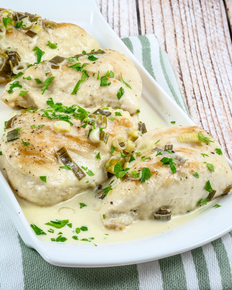 Baked chicken breasts topped with creamy sauce and green onions.
