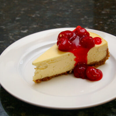 A slice of classic cheesecake with a garnish of cherry pie filling