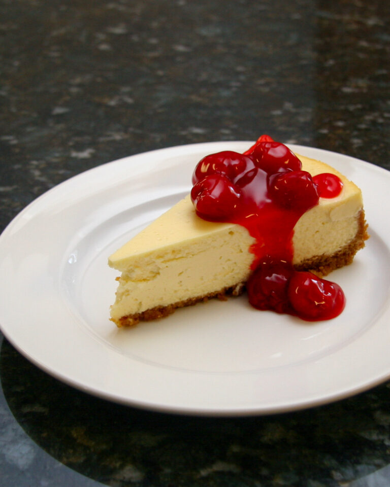A slice of classic cheesecake with a garnish of cherry pie filling