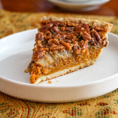 A slice of pumpkin pecan pie on a white plate.